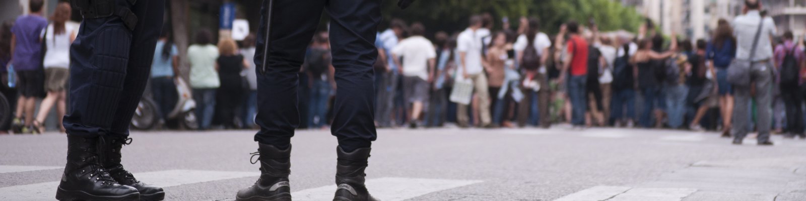 Legs of two police officers standing on the street. Foto via: iStock/Lalocracio
