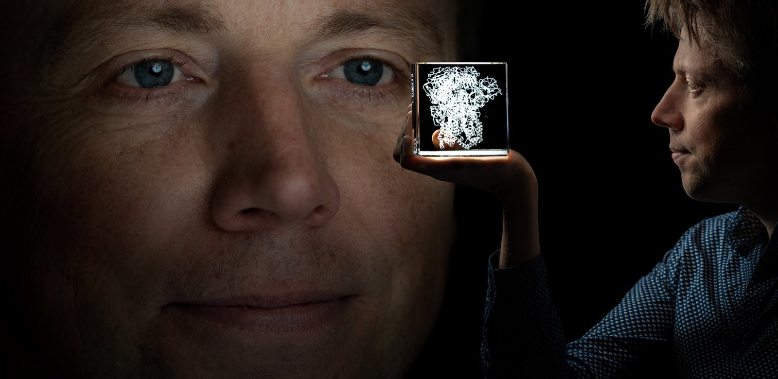 Corona onderzoeker Berend Jan Bosch kijkt van twee kanten naar een kubus met een 3d afbeelding van het coronavirus erin.