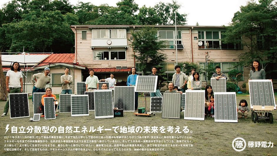 A group photo of Japanese citizens holding small solar panels in front of them