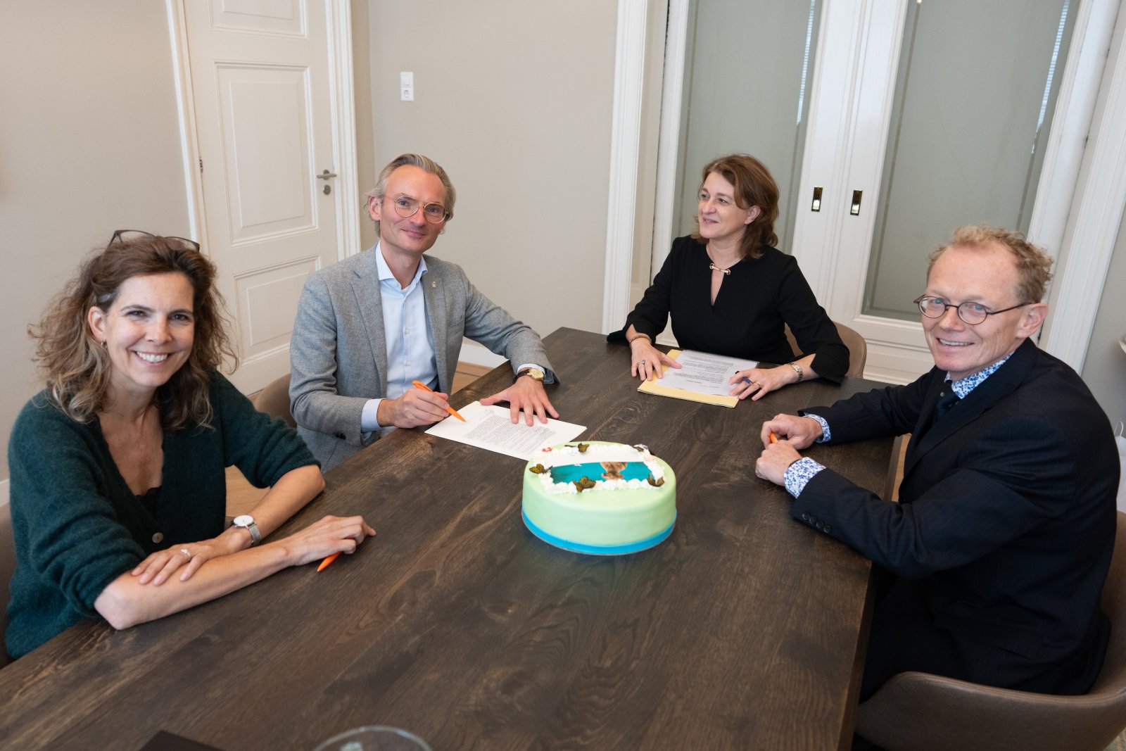 Debbie Jaarsma (l), Nanning Mol (tweede van links), en Paul Mandigers (rechts) zetten hun handtekening bij de notaris om stichting Fairdog op te richten.