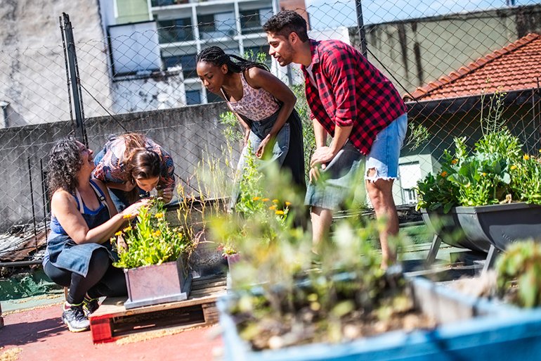 Group of young people on a rooftop in Buenos Aires learning urban gardening from a mid adult woman