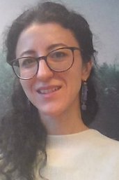 Portrait of researcher Tatiana Sokolova. She has dark, long hair, wears black frames and a white top.