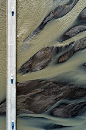 Cars driving on bridge over glacial river, aerial view, South Iceland