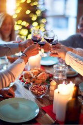 Vier mensen proosten met rode wijn boven tafel