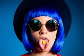 Jonge vrouw met blauw haar en een pilletje op haar tong