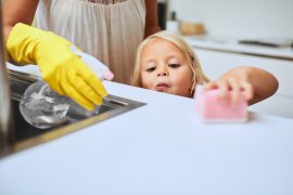 Meisje helpt moeder mee met schoonmaken van de keuken