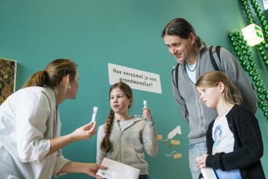 Kinderen, oude en onderzoekers bekijken schimmelmonsters in Universiteitsmuseum