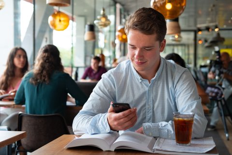 Een student voert een chatgesprek op zijn smartphone