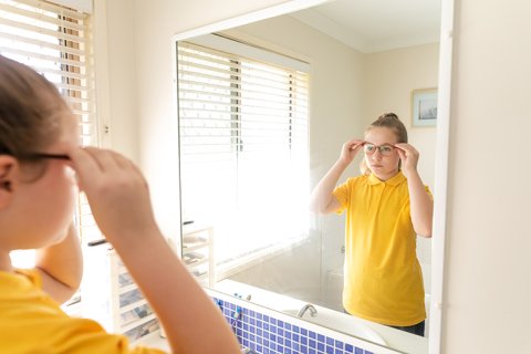 Tienermeisje kijkt in de spiegel naar zichzelf © iStockphoto.com/Thurtell