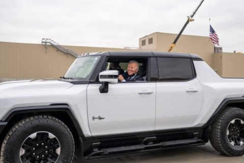 Joe Biden smiling and riding a white electric hummer