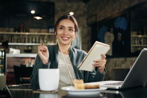 Jonge vrouw in cafe met laptop