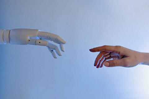 Een hand van een robot en een menselijke hand reiken naar elkaar