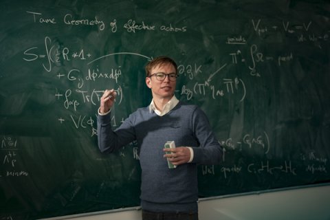 Thomas Grimm standing before a blackboard