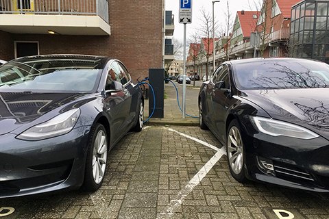 Twee electrische auto's worden geladen aan een oplaadpaal