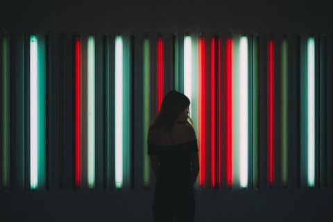 Vrouw in het donker, tegen neon verlichte achtergrond