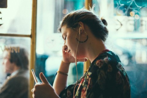 Jonge vrouw luistert met oordopjes, Foto: Siddharth Bhogra via Unsplash