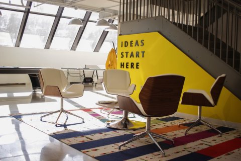 Hip kantoor van een start-up op zolder, gele muur met tekst Great ideas start here