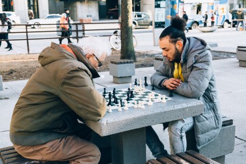 Jonge man en oude man spelen een potje schaken buiten