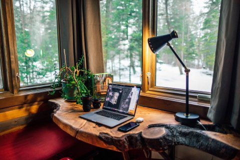 Bureau thuis met uitzicht op bos en laptop aan