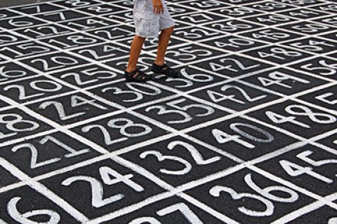 Kind in korte broek loopt over straat waar allemaal getallen op geschreven staan
