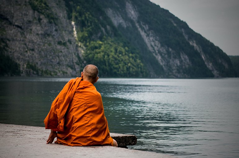 Boeddhistische monnik, wegkijkend aan een meer. Foto: Nicolas Hans, via Unsplash