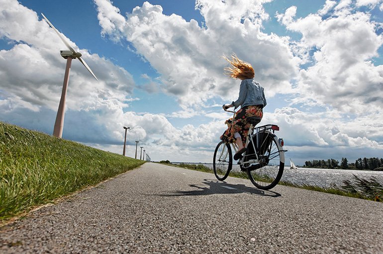 Persoon fietst langs een dijk en windmolens. Foto: © iStockphoto.com/double_p