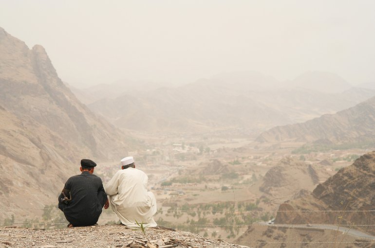 Twee mannen zitten op een berg in Afghanistan © iStockphoto.com/Philmcelhinney