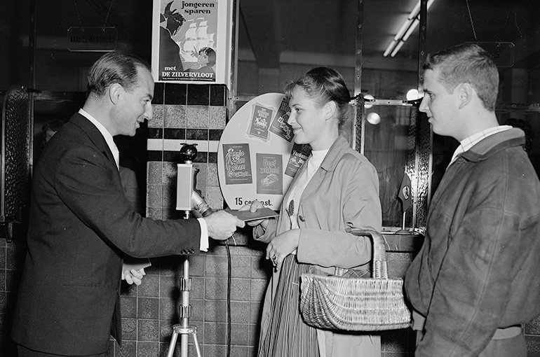 Minister Jo Cals (links) feliciteert jongeren met het openen van een Zilvervlootrekening (1958). Bron: Fotopersbureau, Noord-Hollands Archief (CC0)