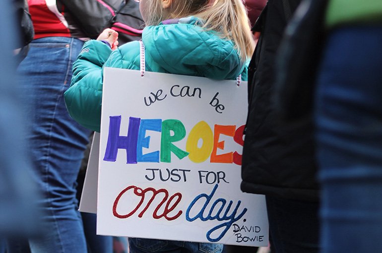 Jong meisje bij een protest met een bord met 'We can be heroes just for one day'. Foto: Jessica Podraza, via Unsplash