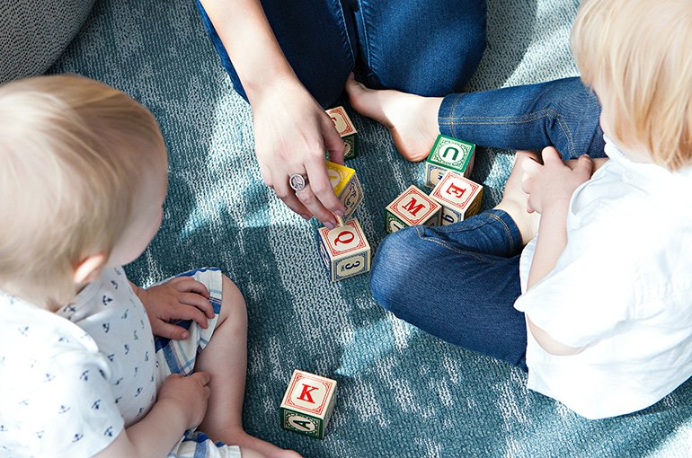 Kinderen spelen met blokken met letters erop. Foto: Marisa Howenstine, via Unsplash