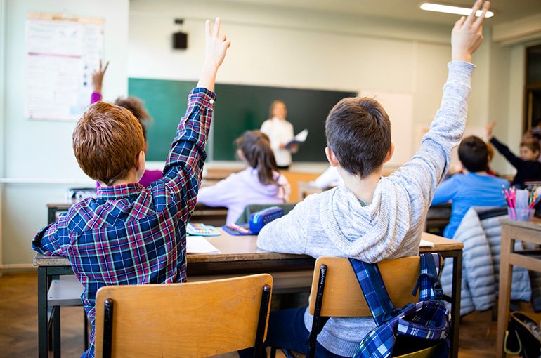 Kinderen in een klaslokaal met de vingers omhoog. © iStockphoto.com/Smederevac
