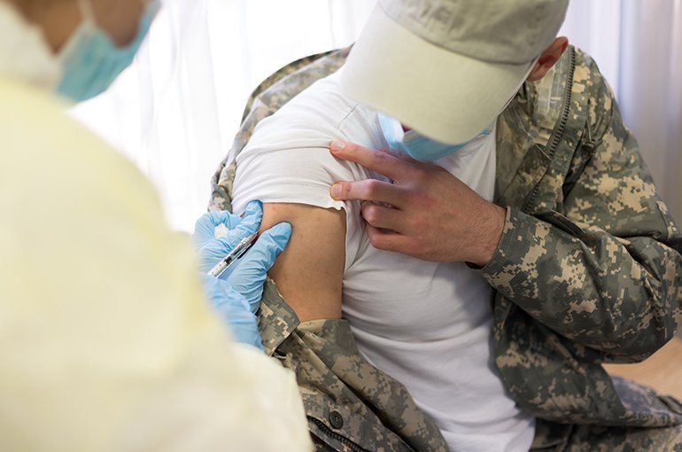 Een legerarts geeft een soldaat een injectie © iStockphoto.com/sasacvetkovic33