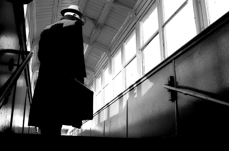 Een zwart-wit foto van een man met aktetas die een trap oploopt en zijn gezicht verborgen houdt © iStockphoto.com/ands456