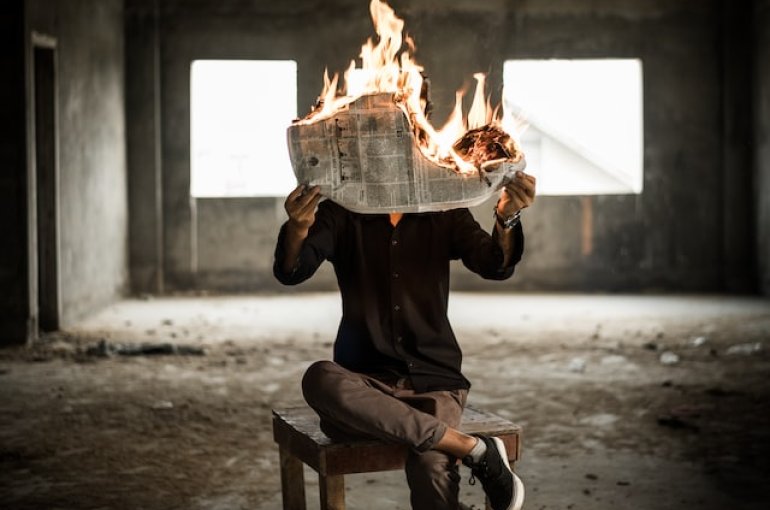Man reading burning newspaper