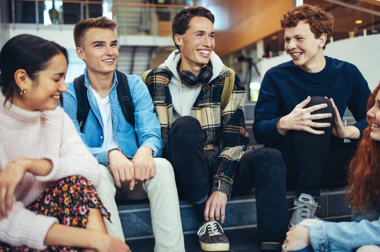 Een groepje jongeren die lachend overlegt in de kantine op school. 