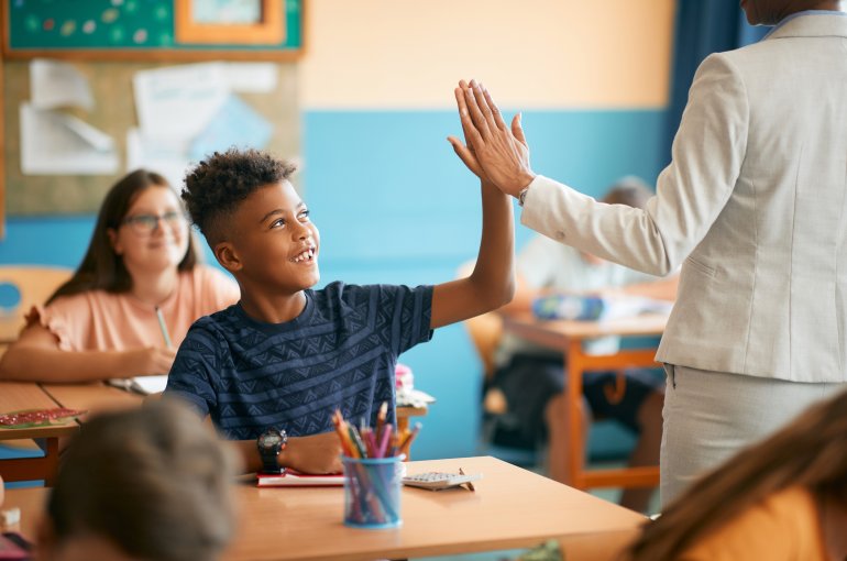 Een leraar geeft een high five aan een student