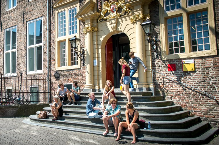 Studenten in de zomer op de trappen voor de ingang van Janskerkhof 3