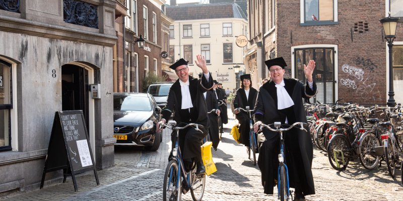 Hoogleraren fietsen in toga door Utrecht